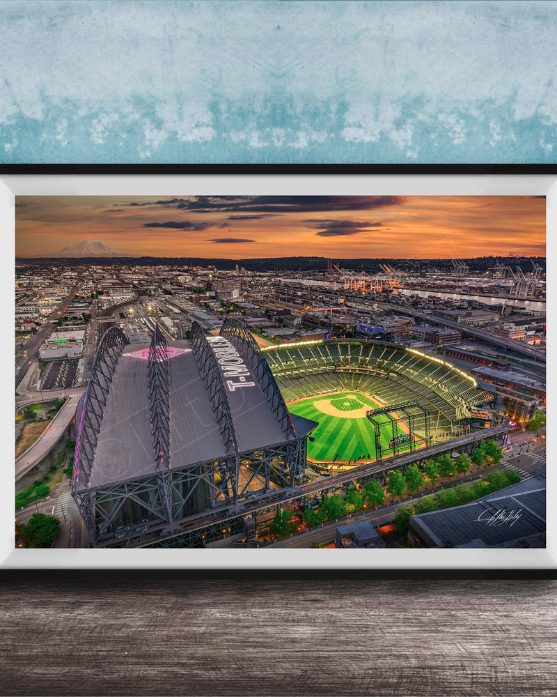 The image is a framed aerial view of a baseball stadium at night, with the stadium lights illuminating the field and surrounding area.