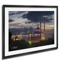 a large mosque with illuminated domes and minarets, set against a dramatic sky at dusk.