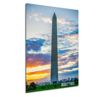 The Washington Monument, a tall obelisk, stands against a colorful sunset sky with clouds.