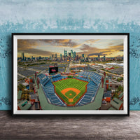 The image is a framed photograph of a baseball stadium in a city, with the city skyline visible in the background.