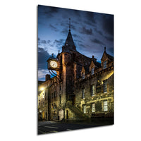 a historic stone building with a clock tower, illuminated at night against a dark sky.