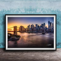 A framed photograph of the skyline of New York City at sunset, with the Brooklyn Bridge and other skyscrapers visible in the background.