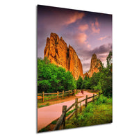 a scenic landscape with a winding path leading through a lush, green forest, framed by towering red rock formations against a vibrant sky with clouds.
