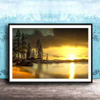A framed photograph depicting a serene landscape with a lake, trees, and a sunset over the water.