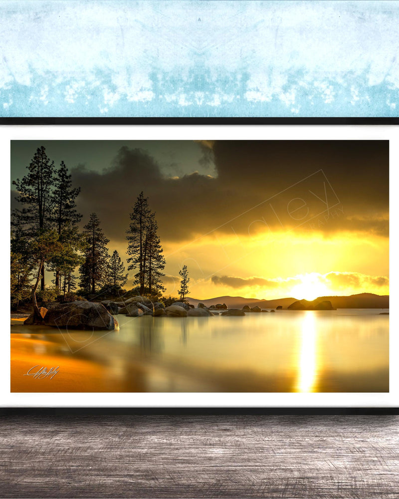 A framed photograph depicting a serene landscape with a lake, trees, and a sunset over the water.
