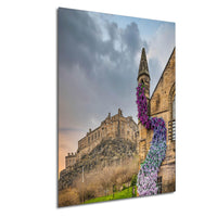 A stone castle with a tower and a colorful flower arrangement on the side, set against a cloudy sky.