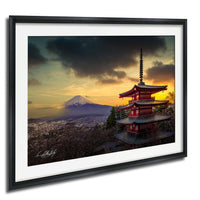 A framed photograph depicting a red pagoda with a mountain in the background, set against a dramatic sky with clouds and a sunset.