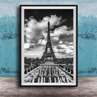 A black and white photograph of the Eiffel Tower in Paris, France, with a cloudy sky in the background.