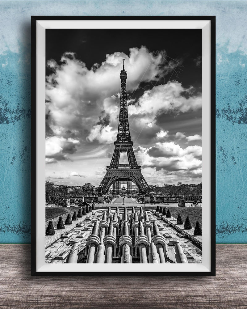 A black and white photograph of the Eiffel Tower in Paris, France, with a cloudy sky in the background.