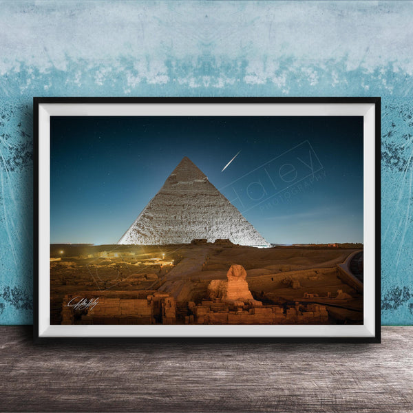 A framed photograph of the Great Pyramid of Giza at night, with the pyramid illuminated against a dark blue sky.