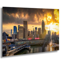 a city skyline at sunset, with tall buildings and a body of water in the foreground.